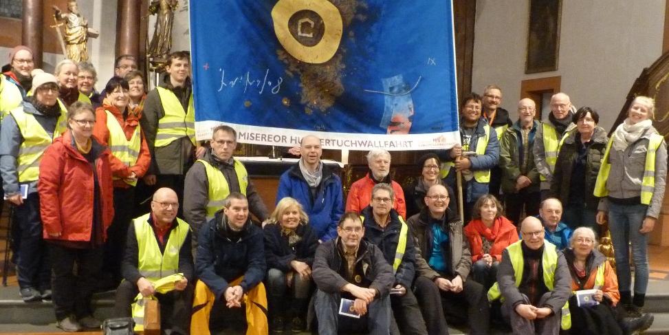 Das mitgetragene Hungertuch aus 2019 zeigt u. a. kräftig blaue Farben und einen goldenen Kreis.