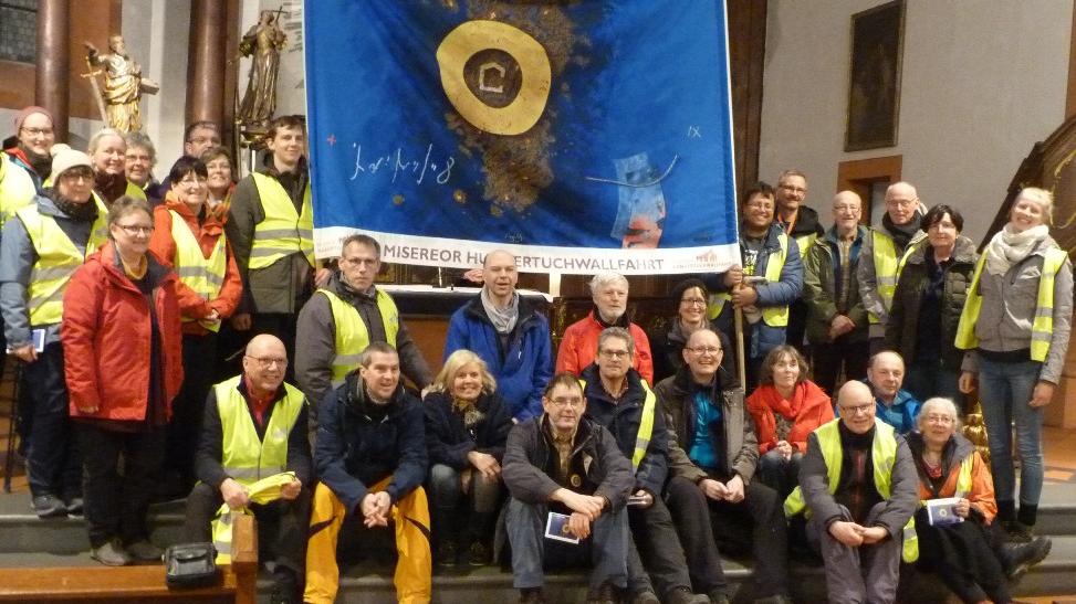 Das mitgetragene Hungertuch aus 2019 zeigt u. a. kräftig blaue Farben und einen goldenen Kreis.