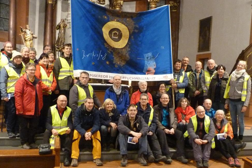 Das mitgetragene Hungertuch aus 2019 zeigt u. a. kräftig blaue Farben und einen goldenen Kreis.