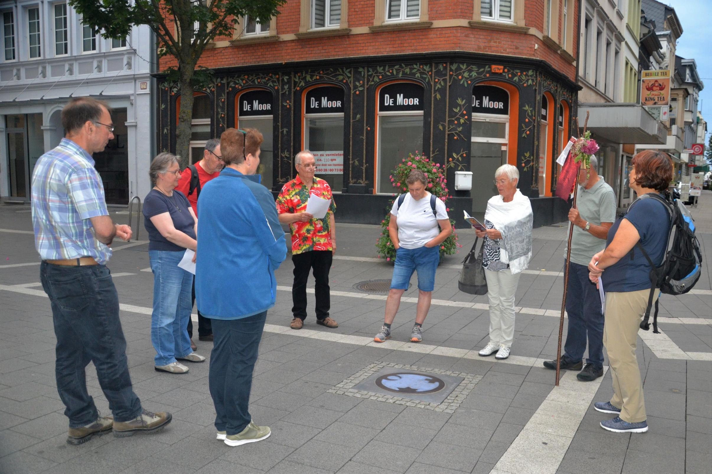 Die Pilgergruppe steht um den 'Engel der Kulturen', der im Straßenpflaster eingelassen ist.