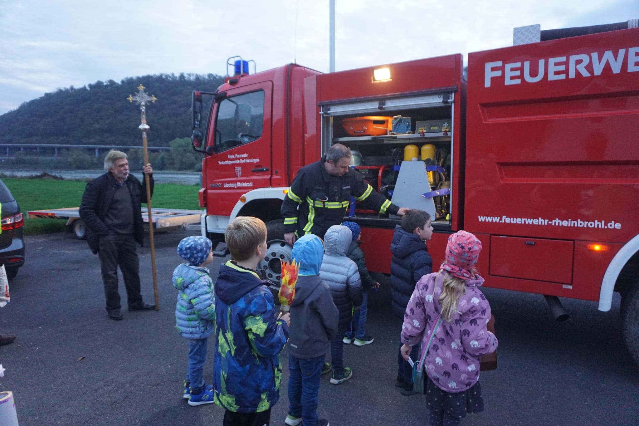 Kinder bewundern das geöffnete Feuerwehrauto, das ihnen von einem Feuerwehrmann erklärt wird.