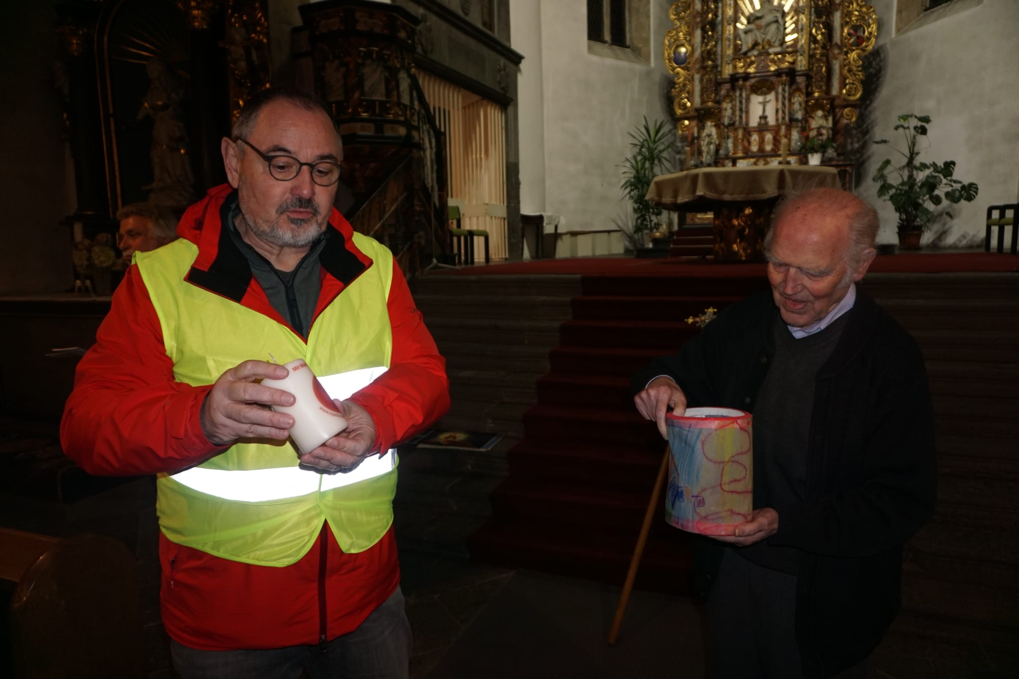 Volker Collinet überreicht Pater Augustinus, der bereits die selbstgebastelte Laterne der KiTa bewundert, eine Martinskerze.