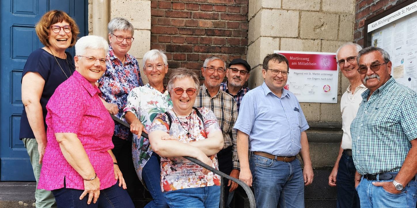 neues Hinweisschild Martinsweg in Engers: 30.09.2026 (c) Andreas Kossmann, Bild bearbeitet mit ChatGPT Mitglieder der Initiativgruppe Martinsweg am Mittelrhein und der Stiftung Sankt Martin Engers trafen sich am neu-angebrachten Hinweisschild an der Engerser Kirche St. Martin.