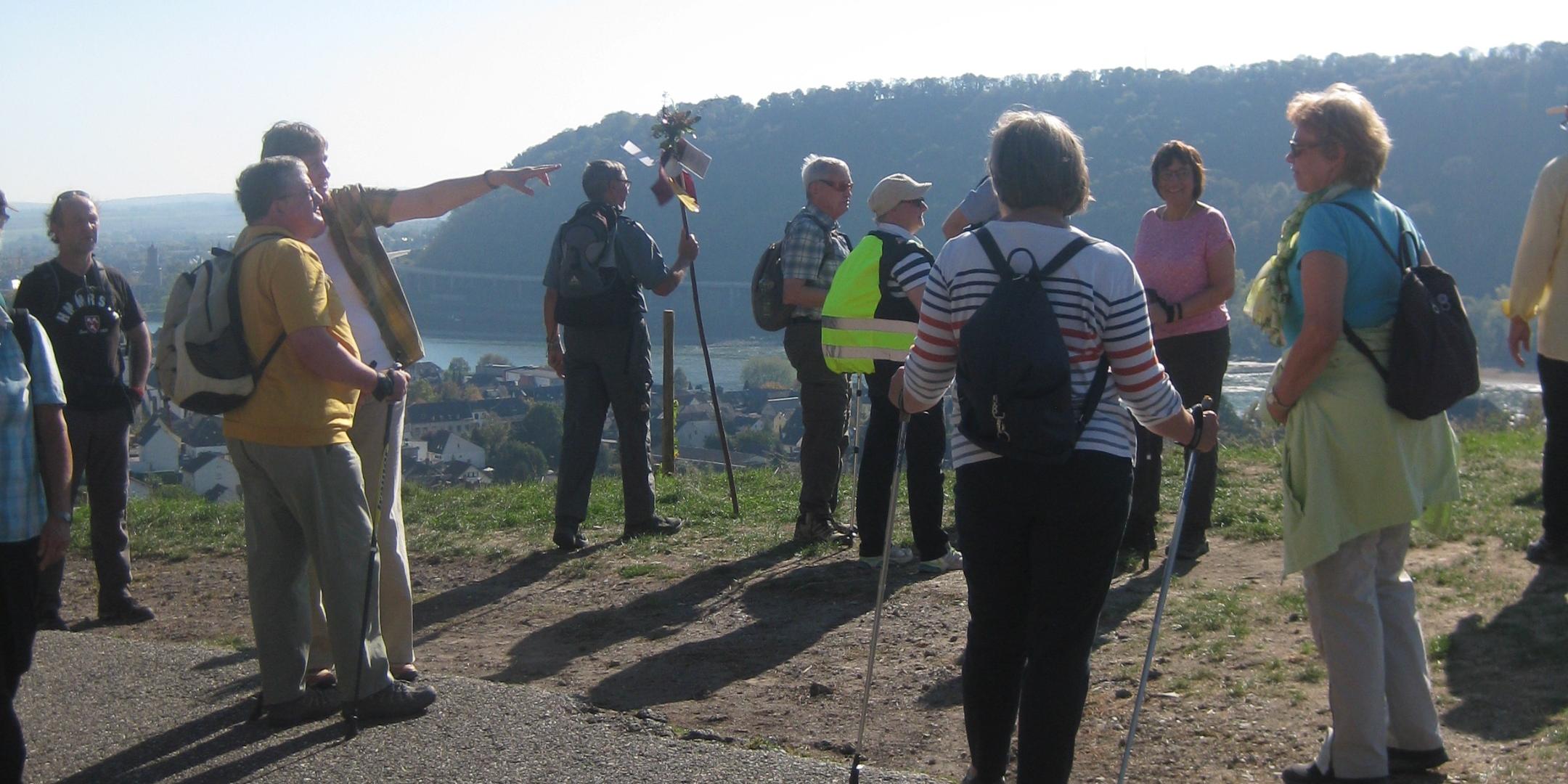 Die Pilger schauen in das Rheintal. Die Sonne wirft ihre Schatten hinter sie.